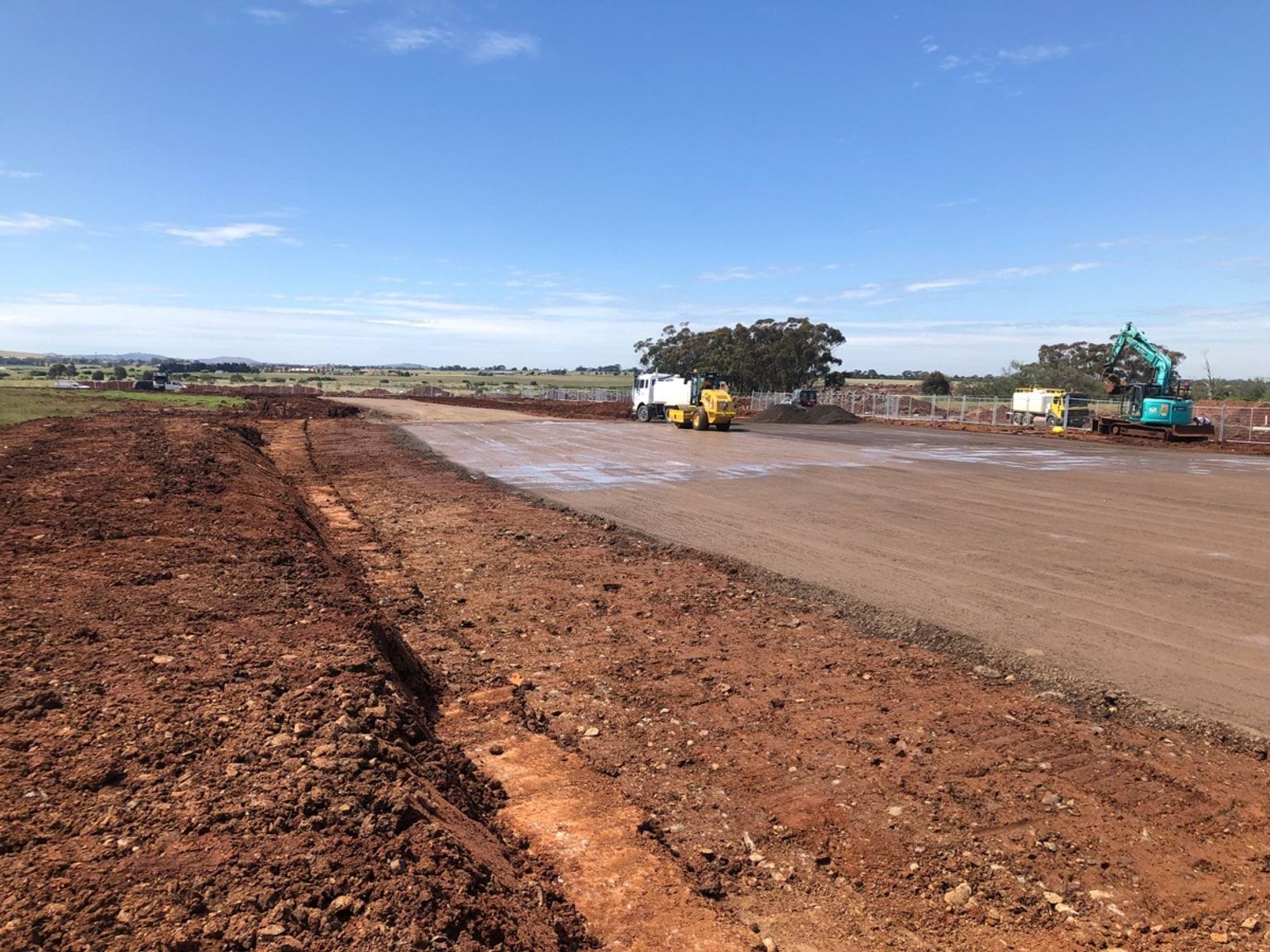 Aintree Specialist School (interim name) - construction photo of site progress in December 2022 - red dirt paddock with a truck and a digger in the background