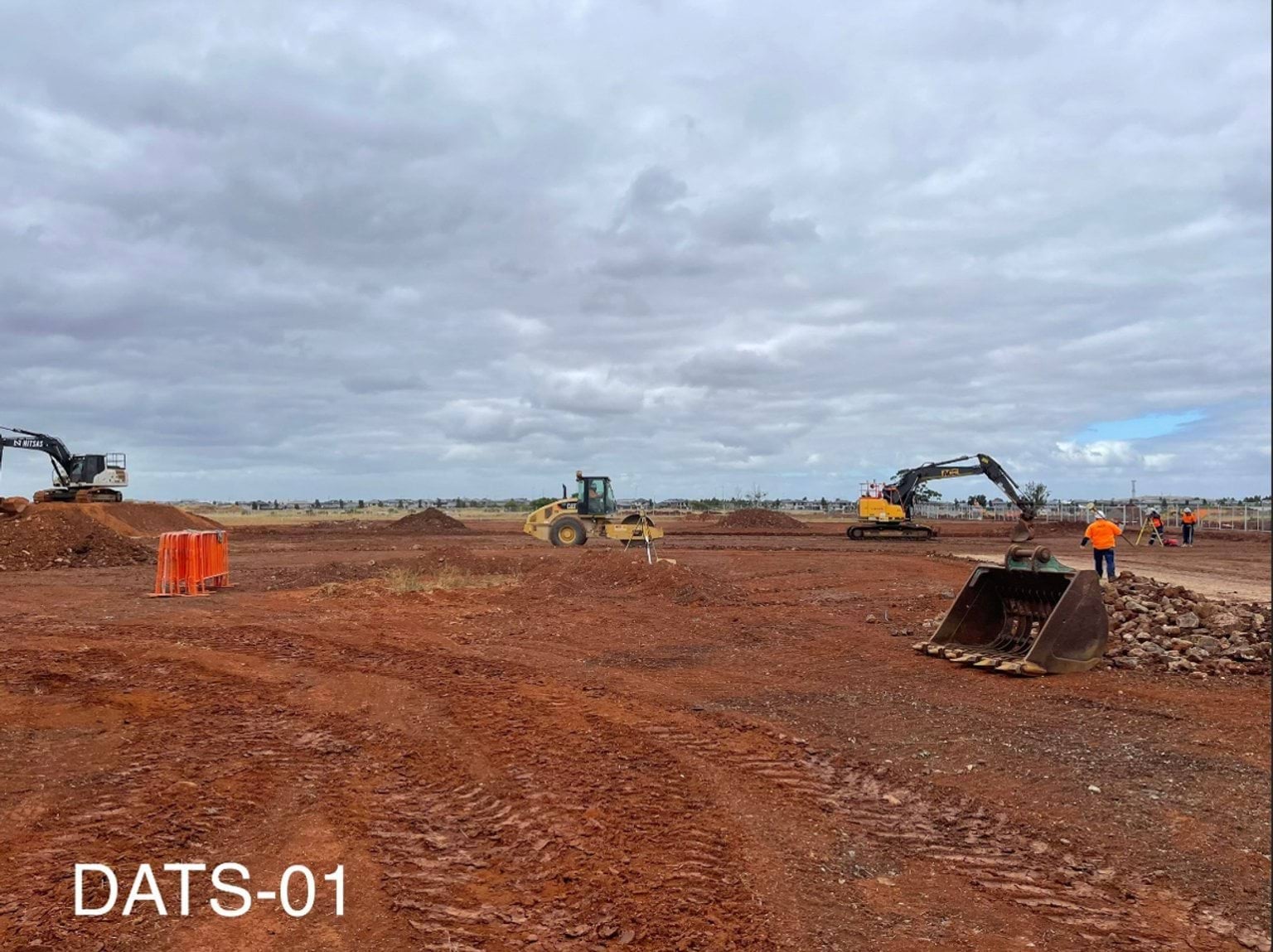 Aintree Secondary School (interim name) - construction photo of site progress in January 2023 - red dirt paddock with 2 cranes, a digger and a worker in high-vis.