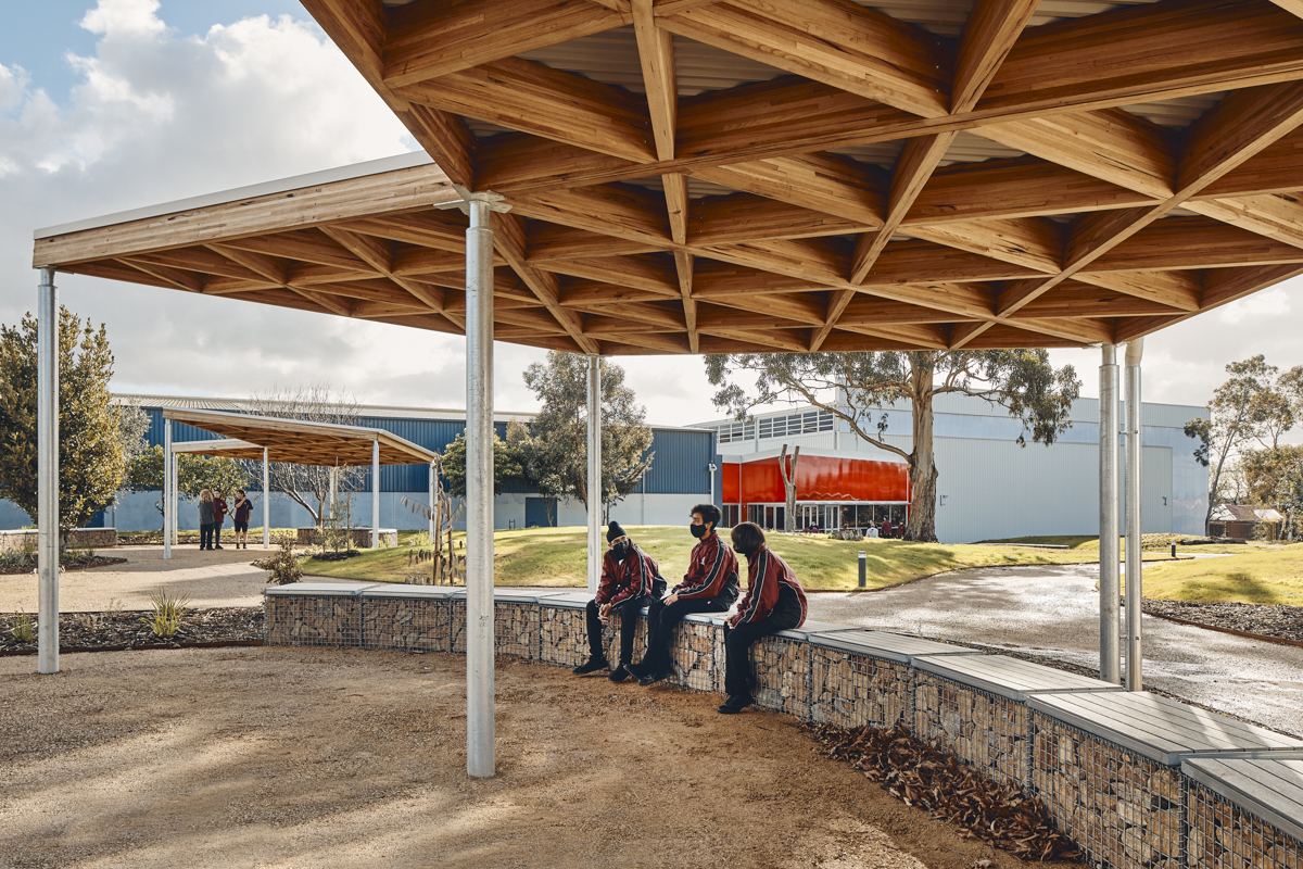Cranbourne Secondary College - photo of students sitting in a covered outdoor area in front of a gymnasium