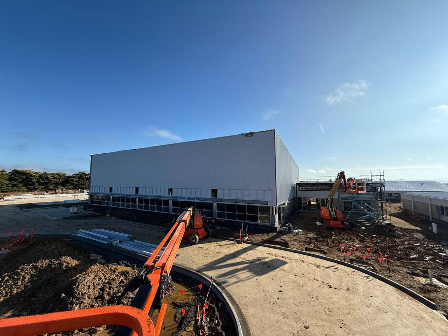 View of the side of constructed buildings. Buildings are situated in muddy paddock
