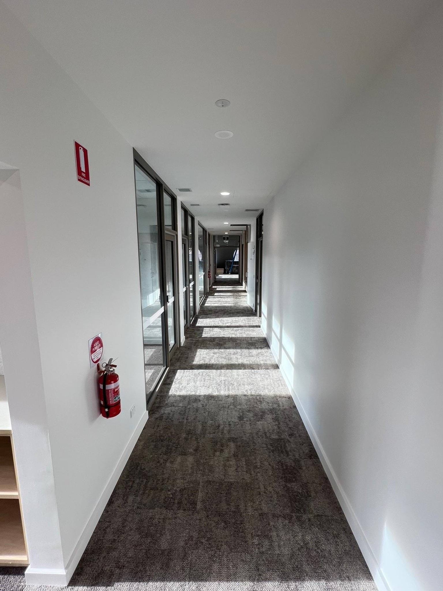 Photograph aimed down the length of a white, light-filled hallway.