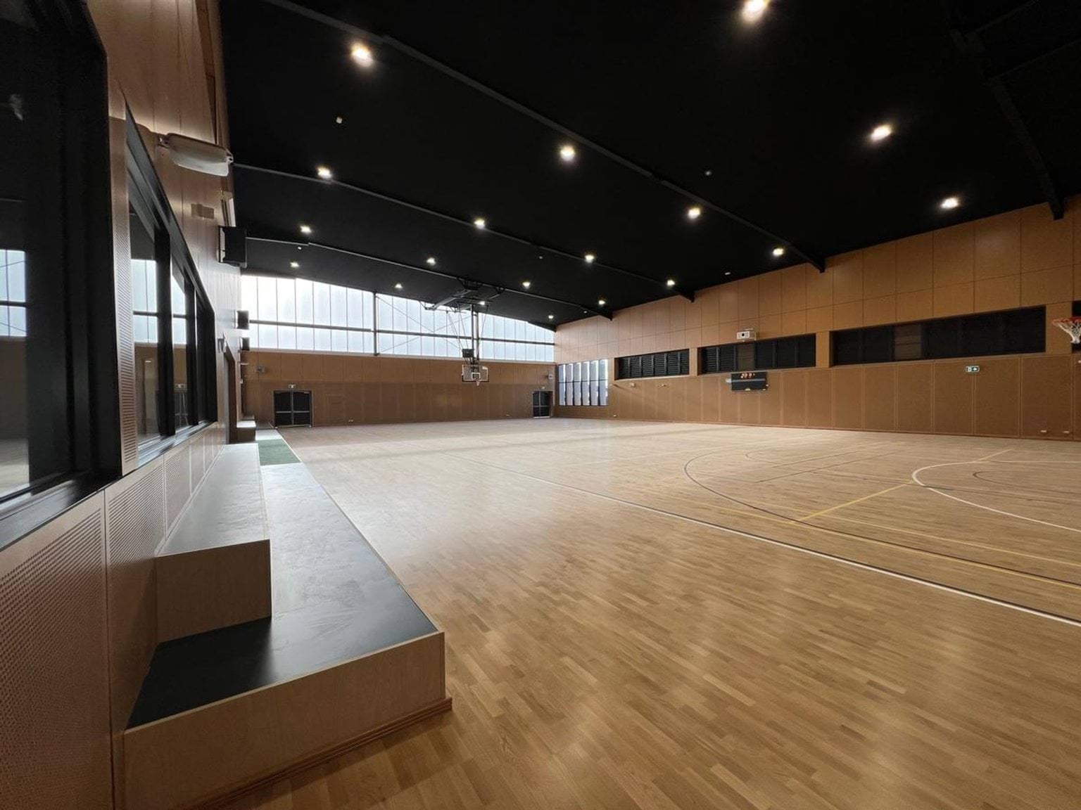 Polished timber finishing on new indoor basketball courts with built in tiered timber seating 