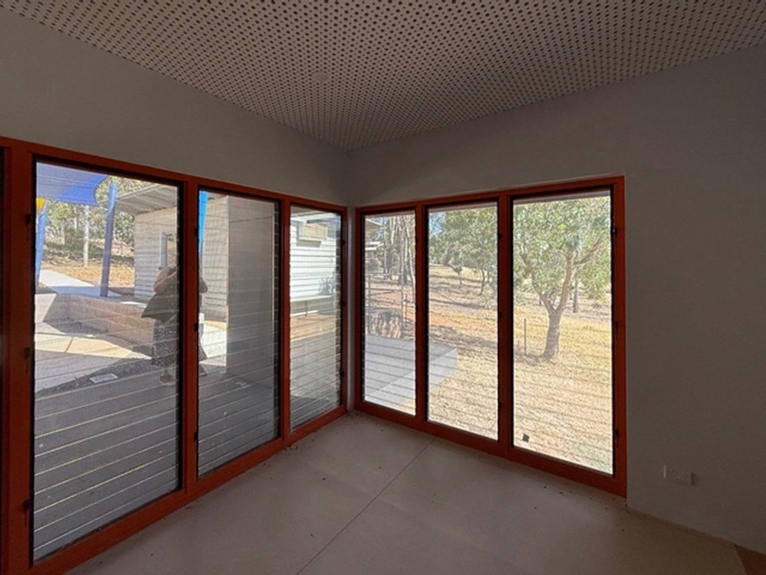 Inside a room at Currawa Primary School. The floor is tiled, and there are large windows through which trees and other school buildings can be seen.