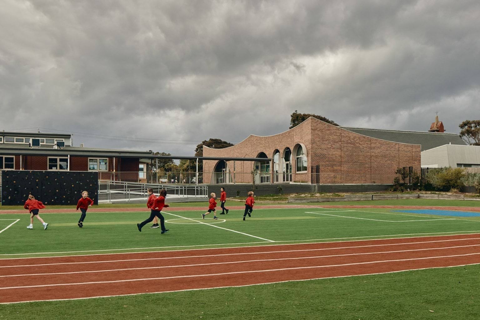 Outdoor photo showing sports field in foreground and school administration building in background.