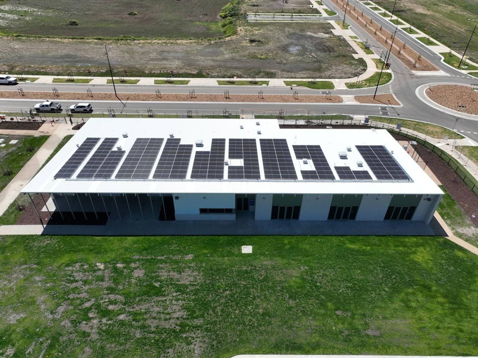 A photo of a new school building at Muyan Primary School taken from a high angle. There are solar panels on the roof, and grass is growing in front of it.