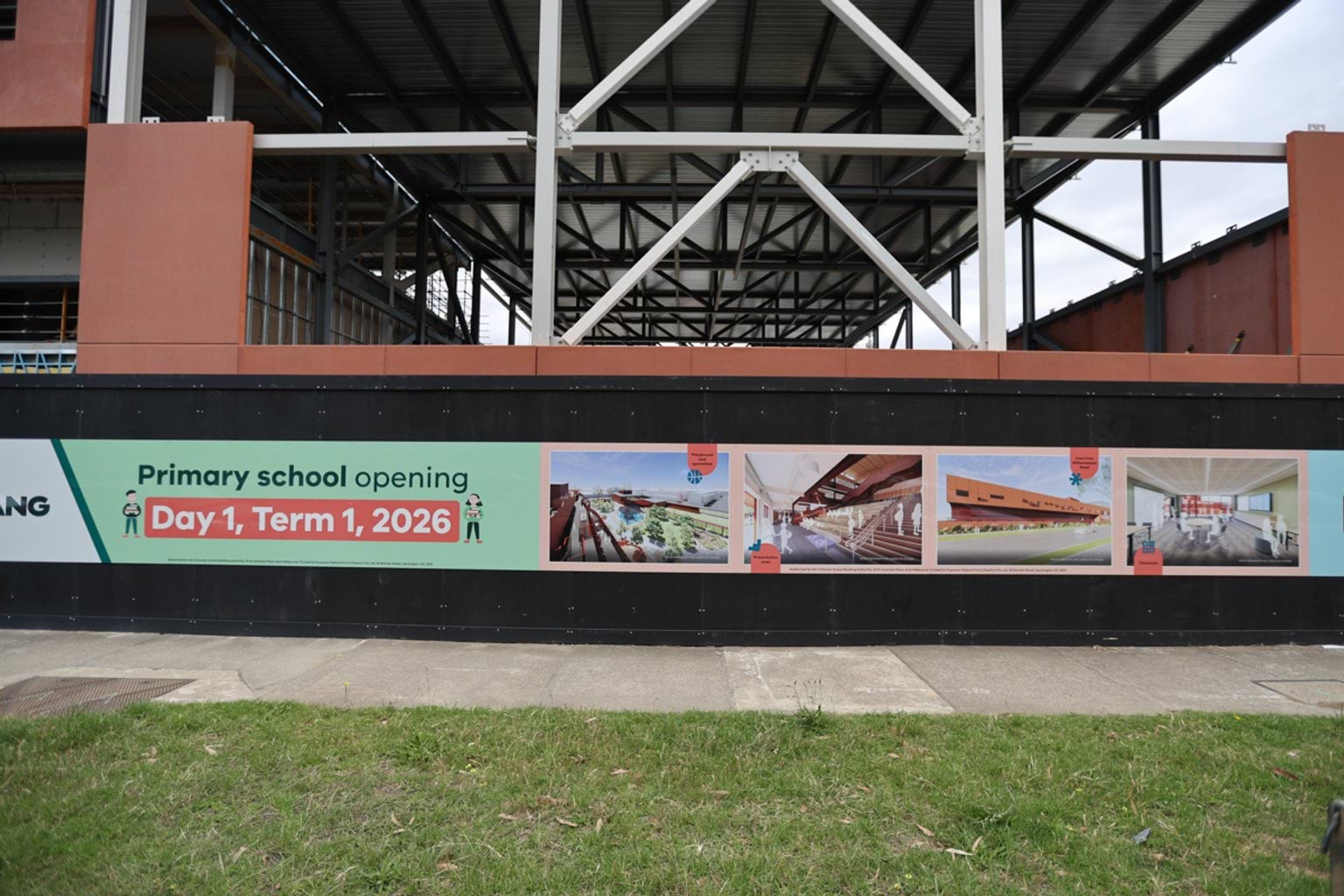 Photo of school building under construction from footpath angle. There is a promotional sign saying "Primary school opening Day 1, Term 1, 2026" with promotional photos of the school.