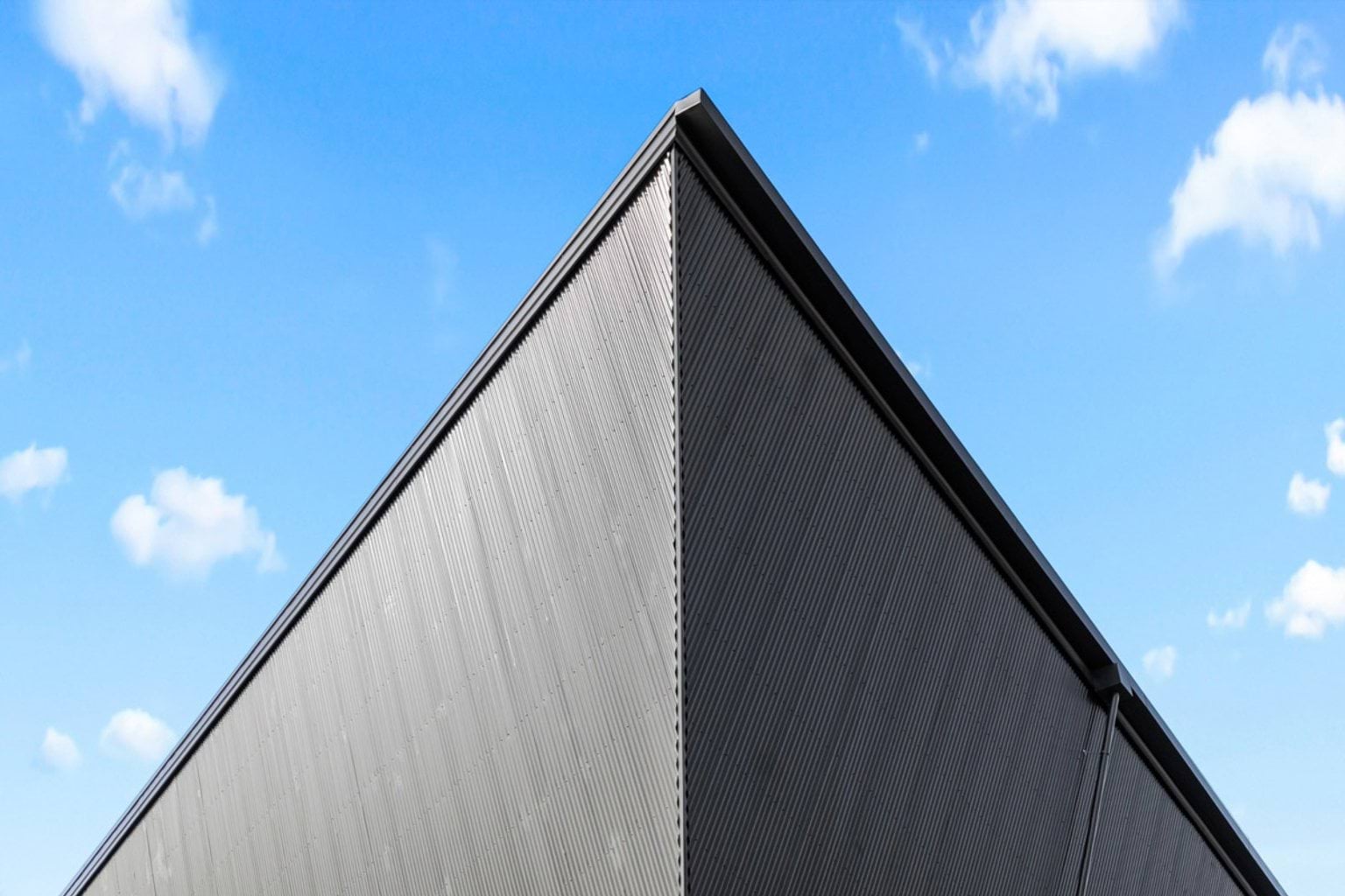 Close-up of the Performing Arts Precinct’s sharp angular roof clad in dark metal panels against a bright blue sky.