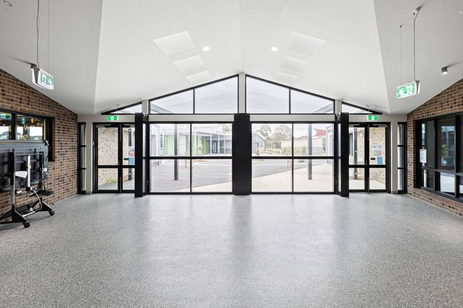 A bright entry foyer with polished flooring and large glass doors opening to the school courtyard.