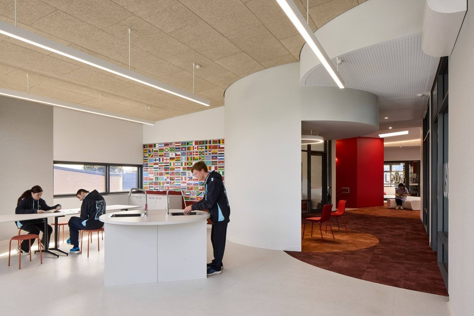 An open learning area with curved white walls and a circular desk. A colourful wall display of international flags adds vibrancy to the space.
