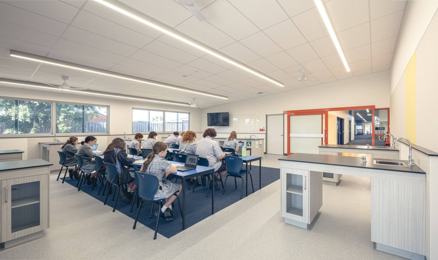 Science classroom with students seated at desks using laptops, large windows and bright interior finishes