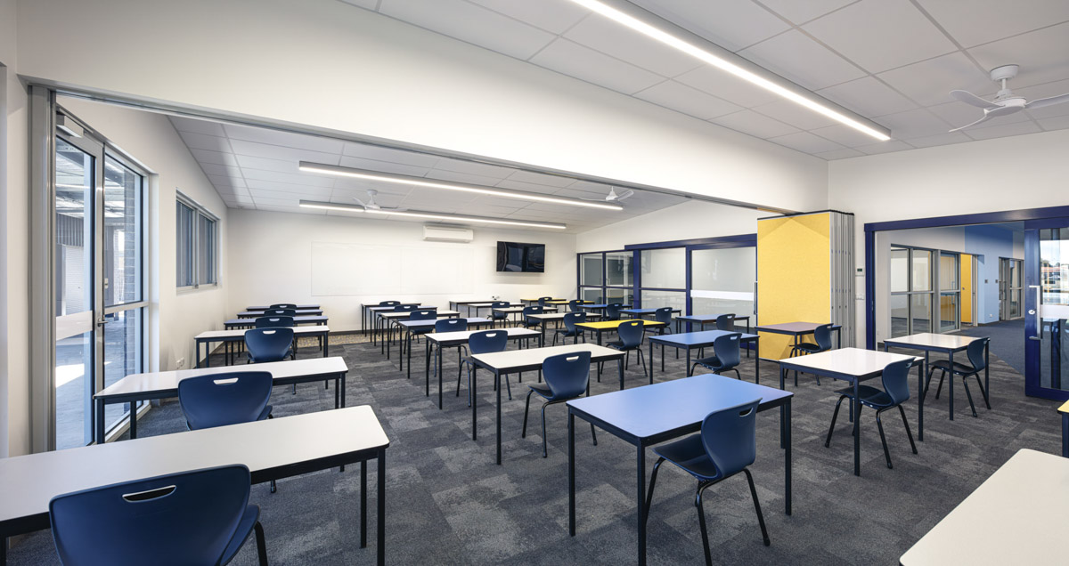 Spacious classroom with rows of desks and chairs, glass partitions and bright white walls