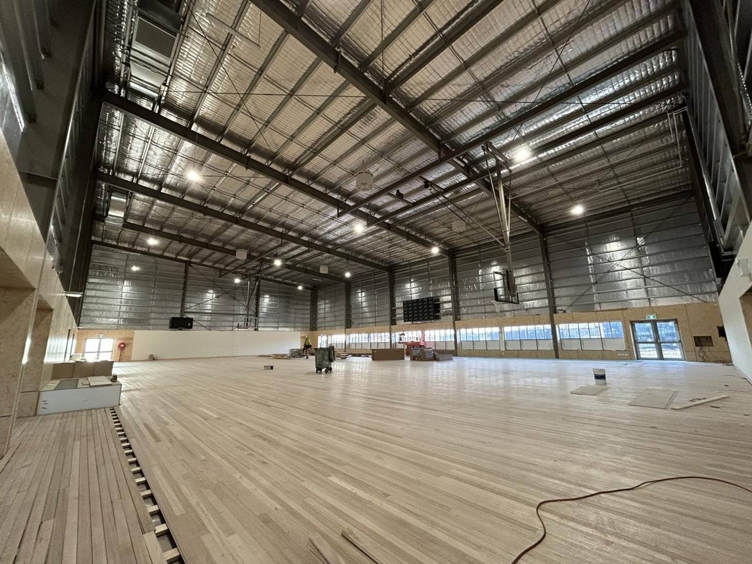 Indoor gym. Floorboards are being added and silver insulation is visible.