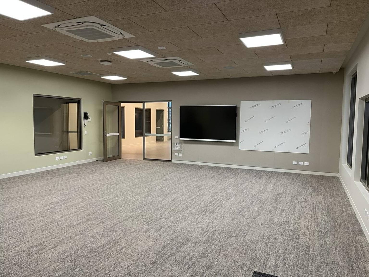 Classroom with screens at the front of the room and doorway leading to hall