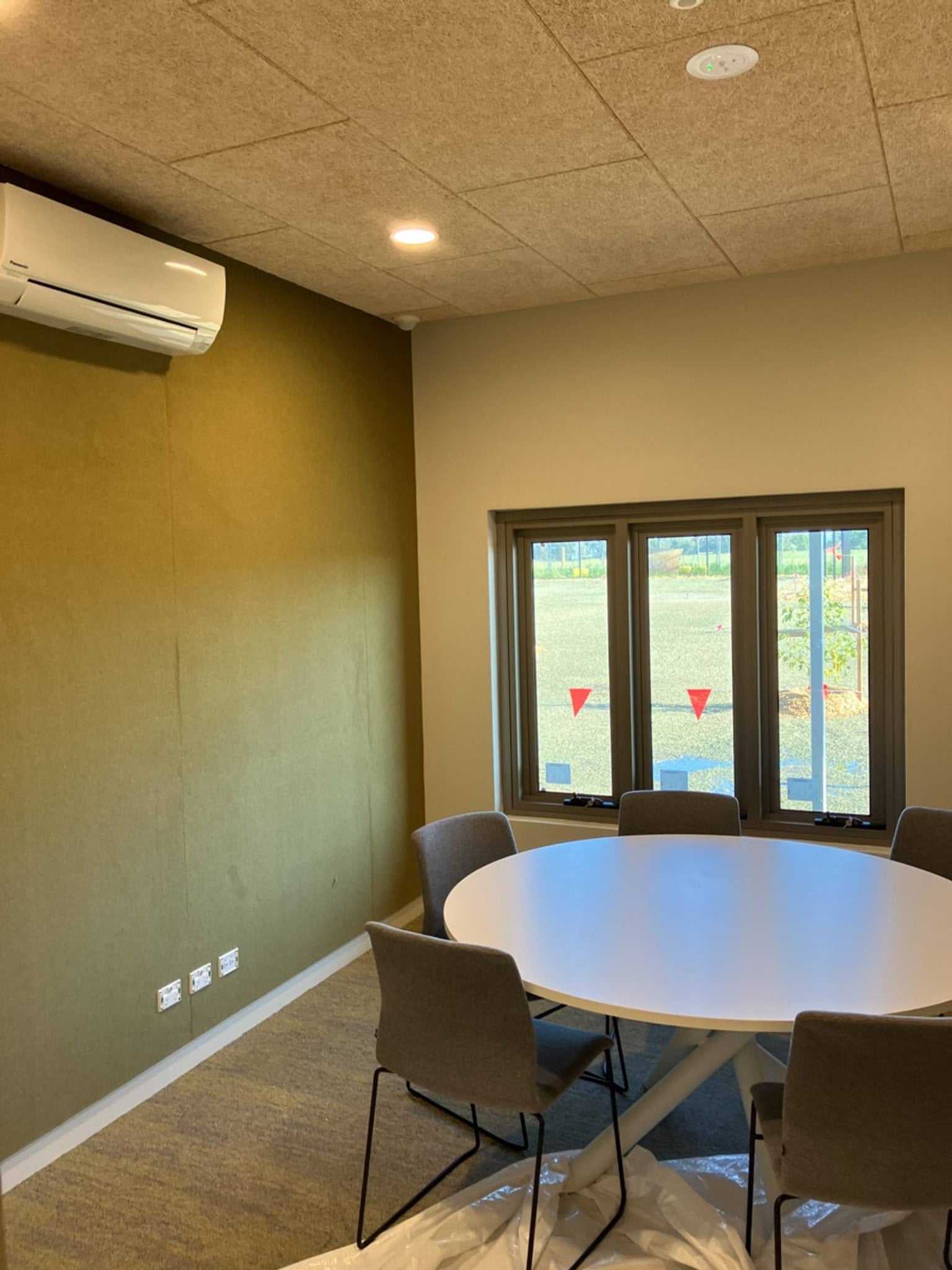 Photo of round table surrounded by chairs inside room with windows and air conditioner