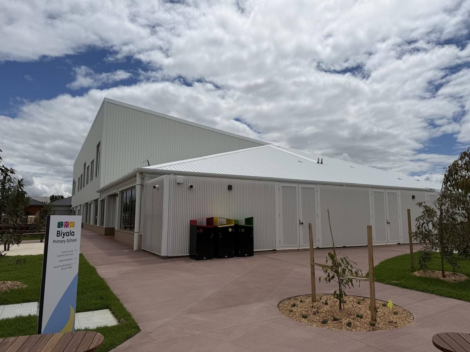 Outside the new Biyala Primary School, looking at a white building. A sign with the school's name is on the left.