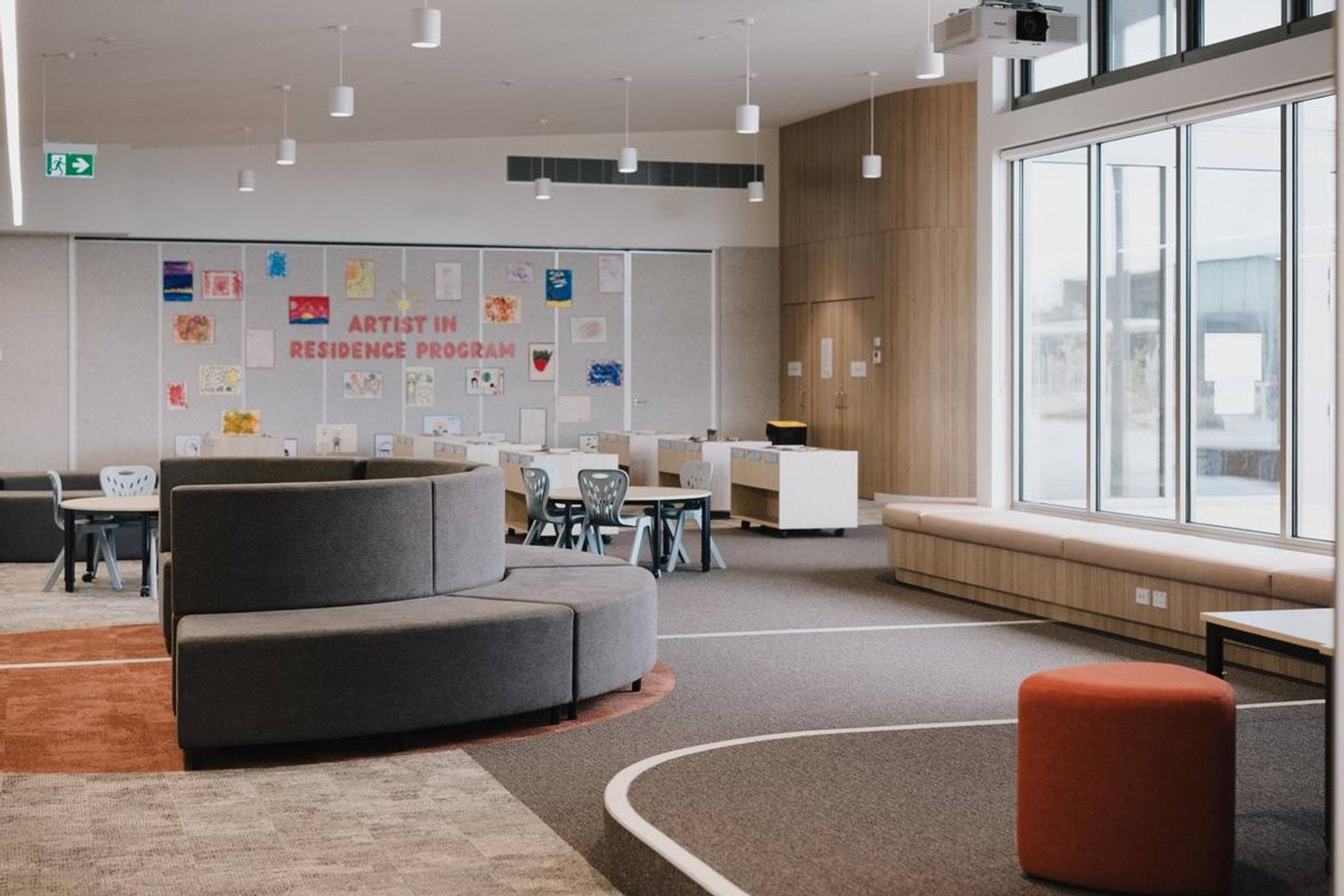 Modern open-plan classroom with flexible seating, large windows and display wall for student artwork