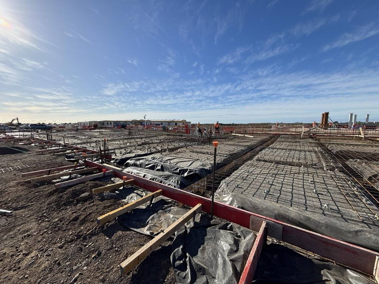 Foundation work with steel reinforcement and formwork prepared for concrete pour across large site