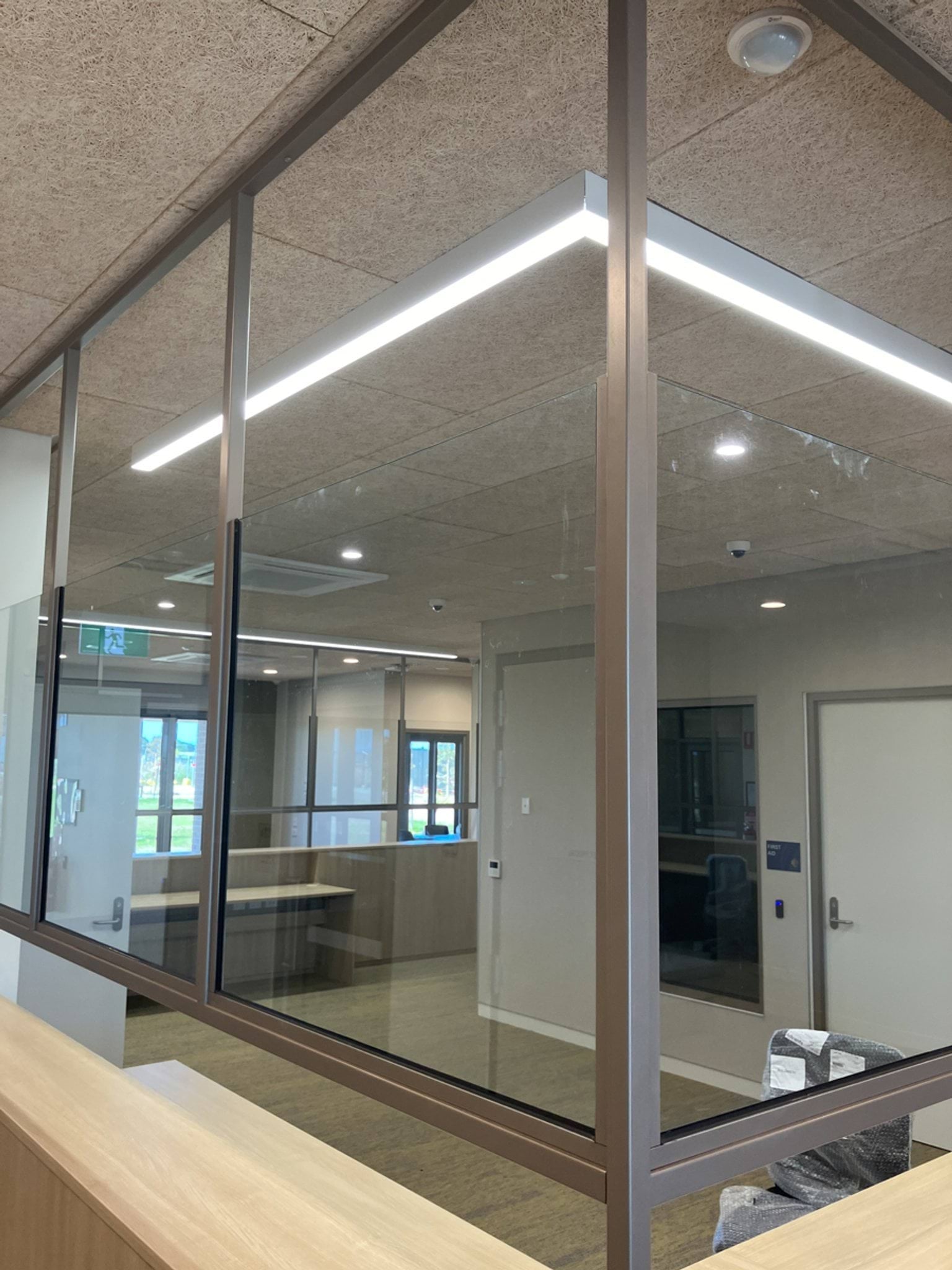 An unfinished reception area with timber counters, glass partitions, and ceiling panels installed.
