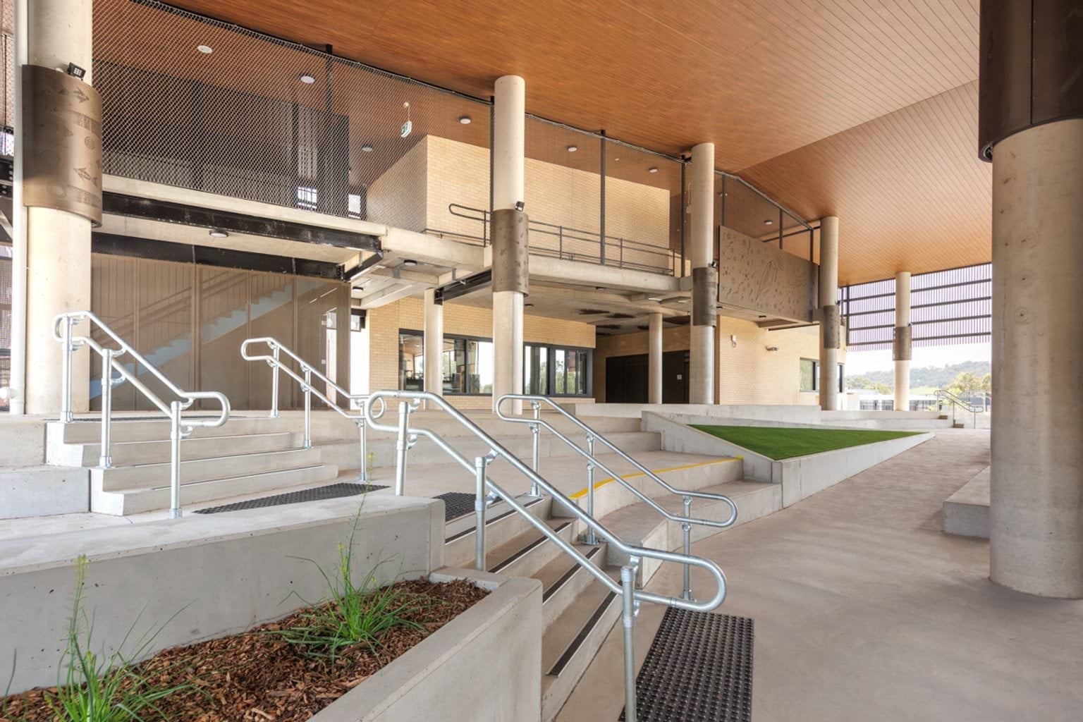 Outside area with concrete steps, metal balustrades, large columns and covered walkways.