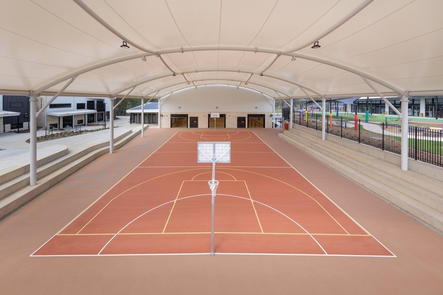 Covered outdoor sports court, marked playing surface and tiered concrete seating.