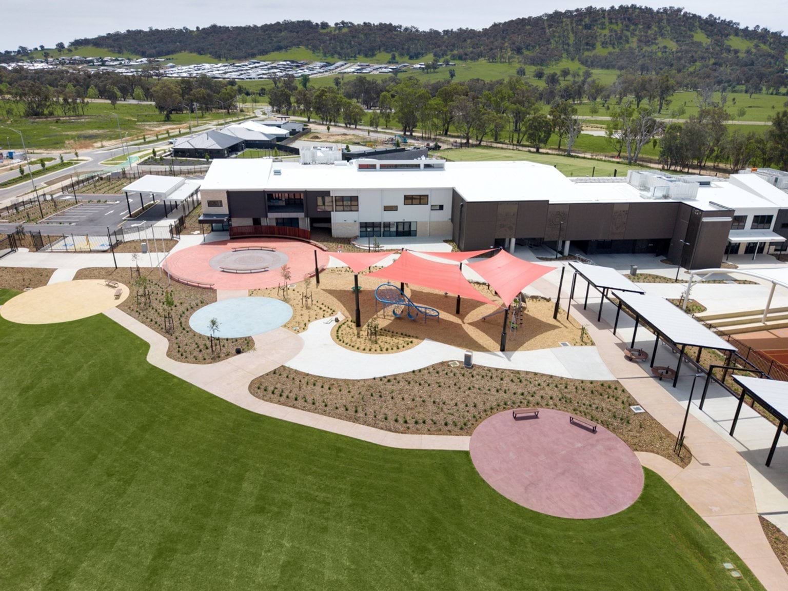 Aerial view of school buildings and outdoor play areas with shade structures and landscaped paths