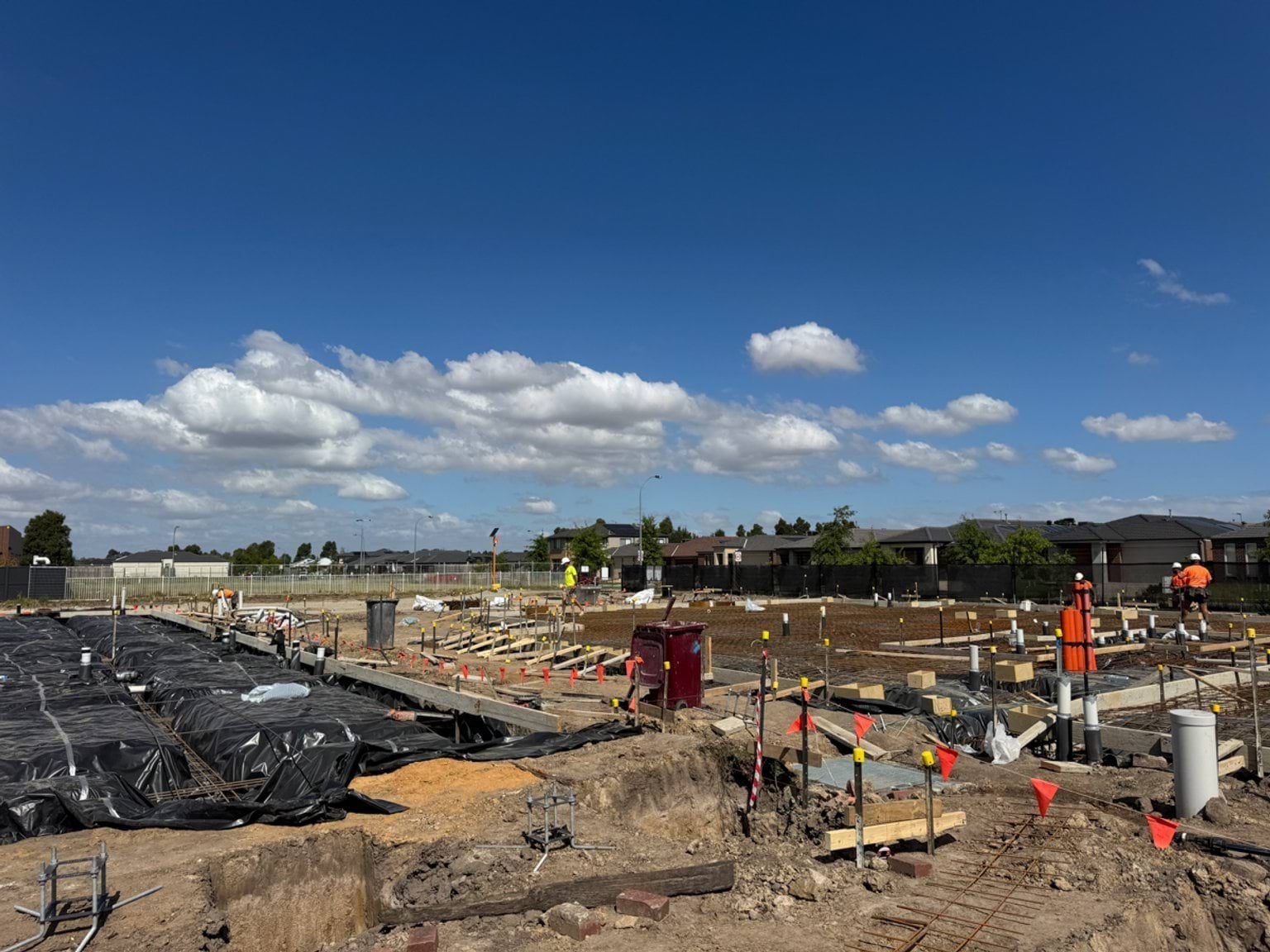 School construction site with services installation underway, including piping and marked foundations.