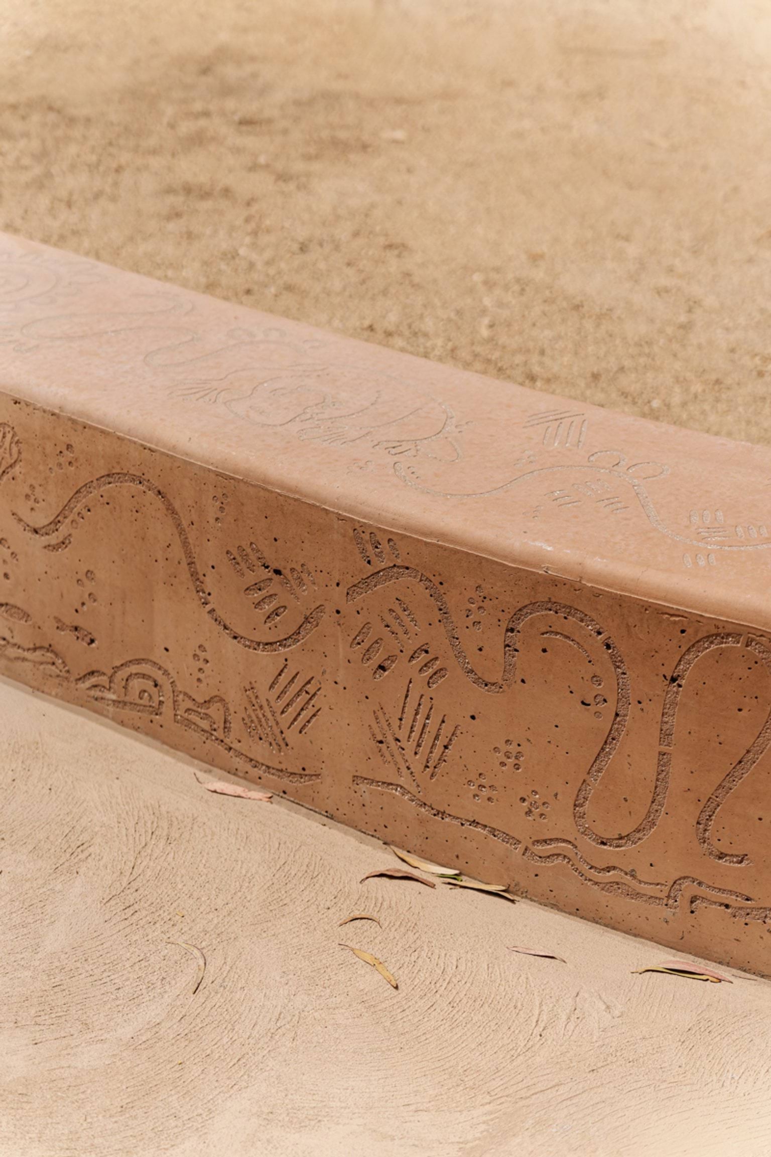 A curved seating wall in the outdoor play area featuring etched patterns and designs inspired by nature.