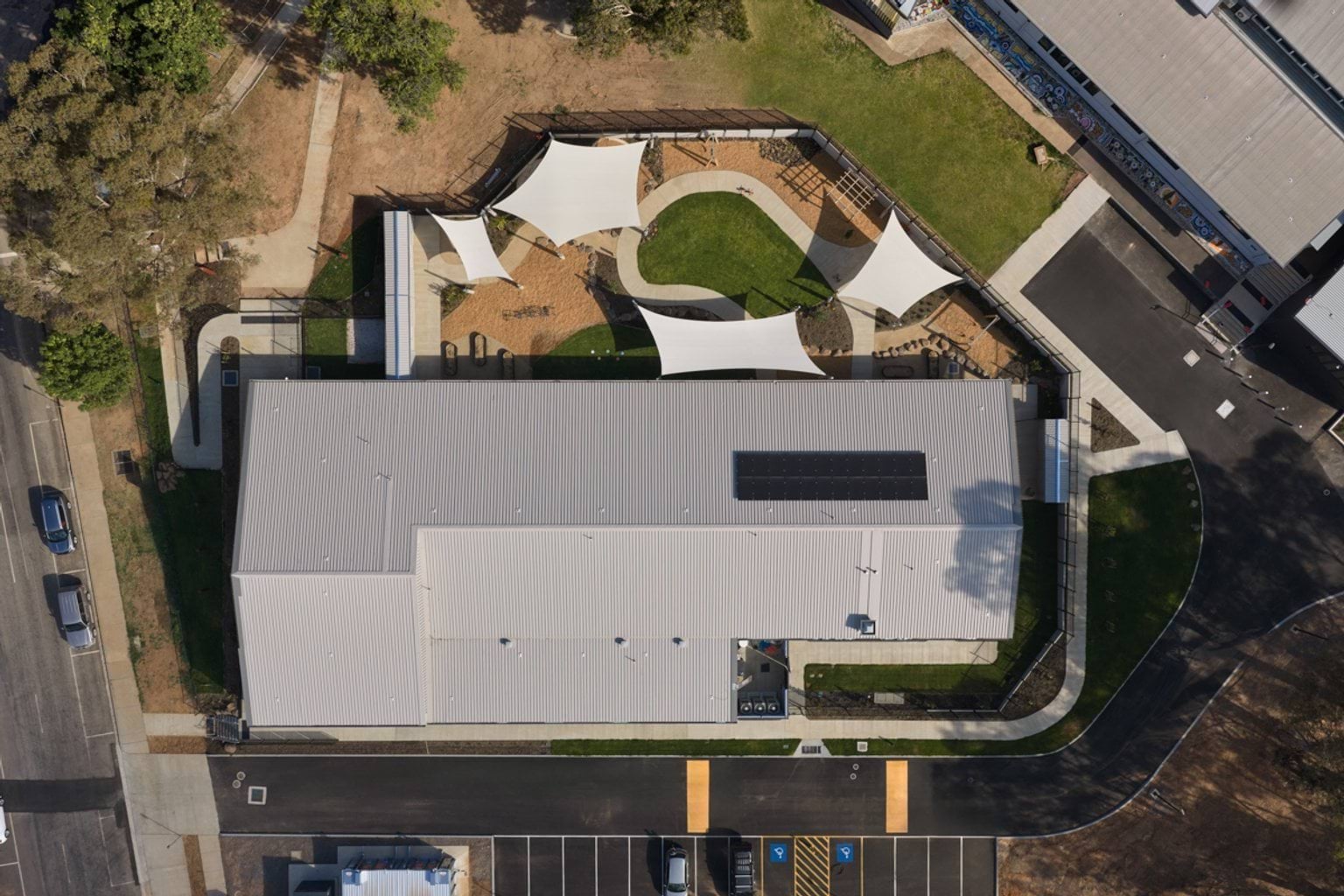 An aerial view of the early learning centre showing the building footprint, shaded outdoor play areas, pathways, and surrounding parking.
