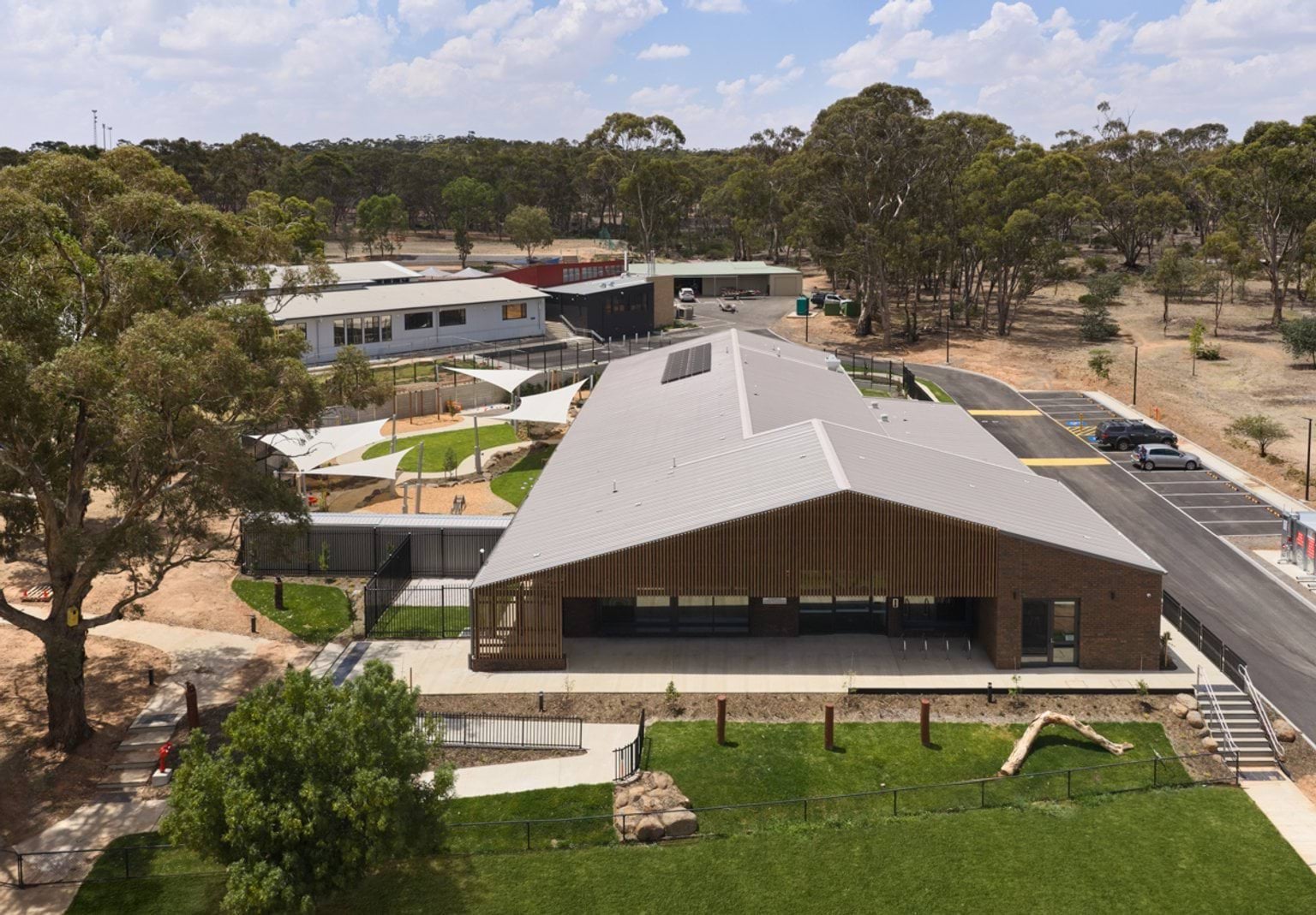 Aerial view of the early learning centre and neighbouring school buildings, with landscaped outdoor play areas beneath shade sails.