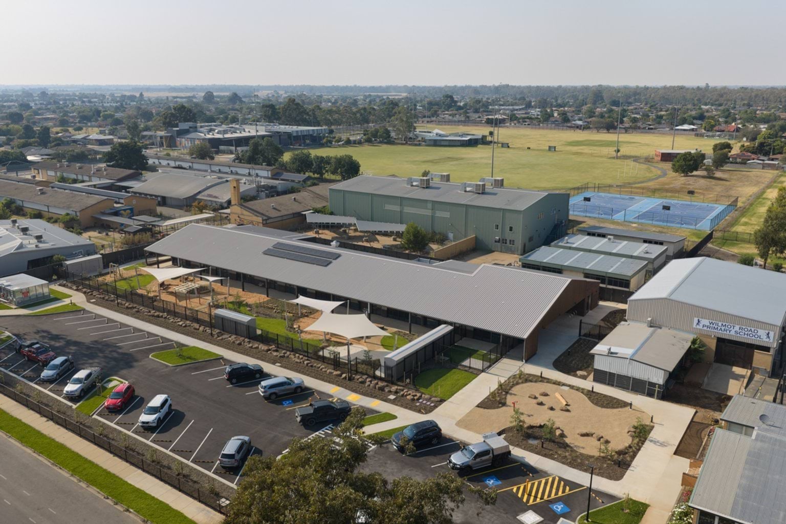 Aerial perspective of the early learning centre and surrounding neighbourhood, showing the main building, outdoor areas, and adjacent school facilities.