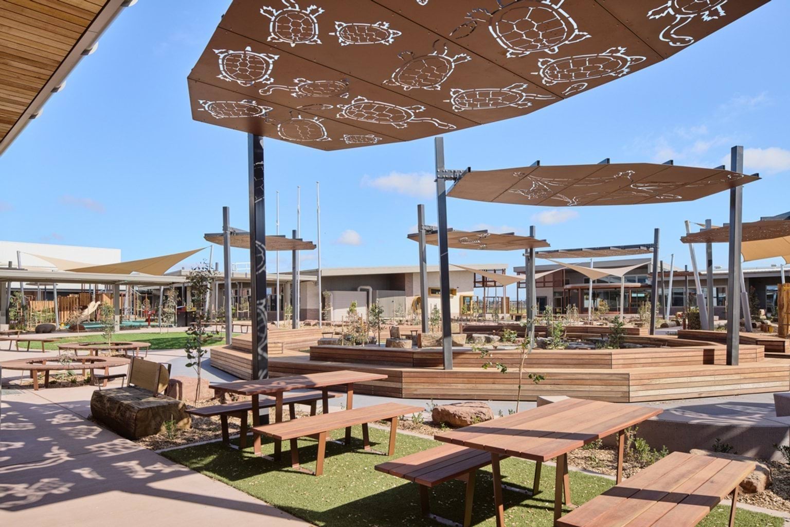 Wooden seats and tables outside underneath shade cloths