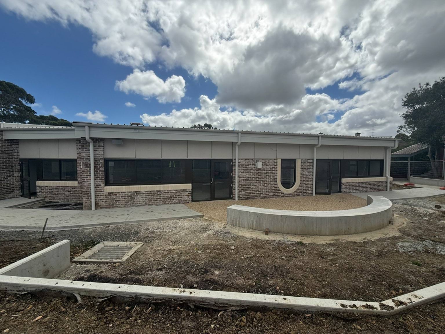 New school building with brick work, windows, and a cloudy blue sky overhead