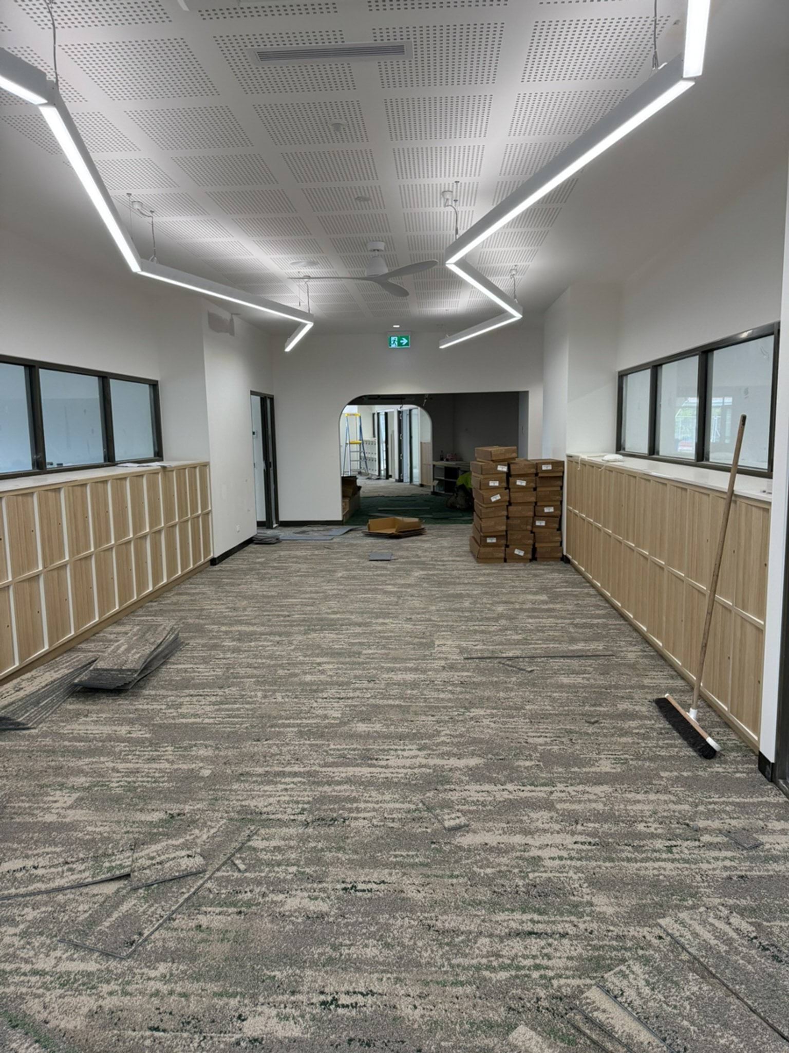Hallway with carpeted floors and shelves off to the sides