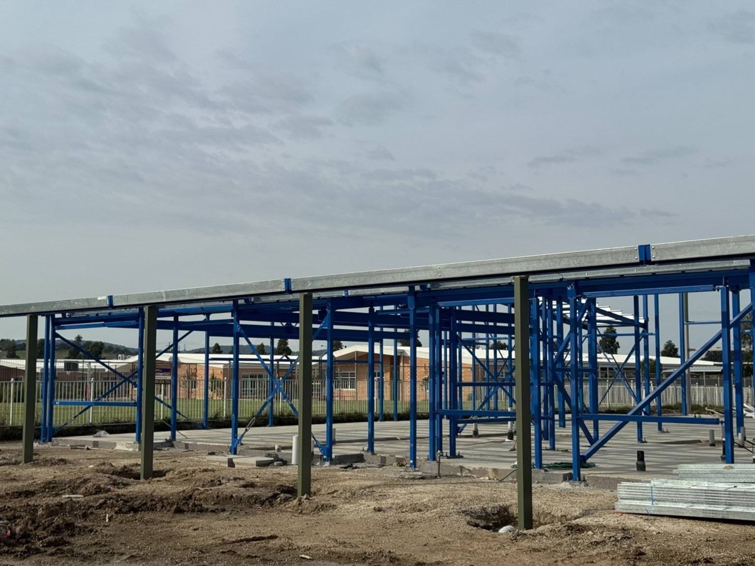 Steel structural frame of a school building with roof decking installed and concrete slab below.