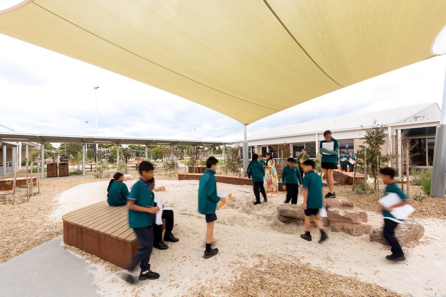 Students walking through covered sandpit play area