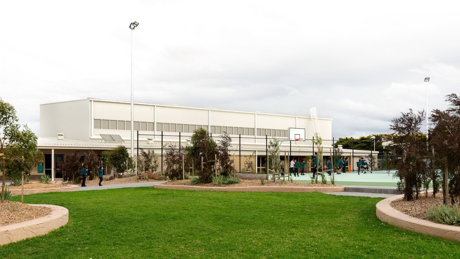 Outdoor green space and garden with basketball courts and school building in background
