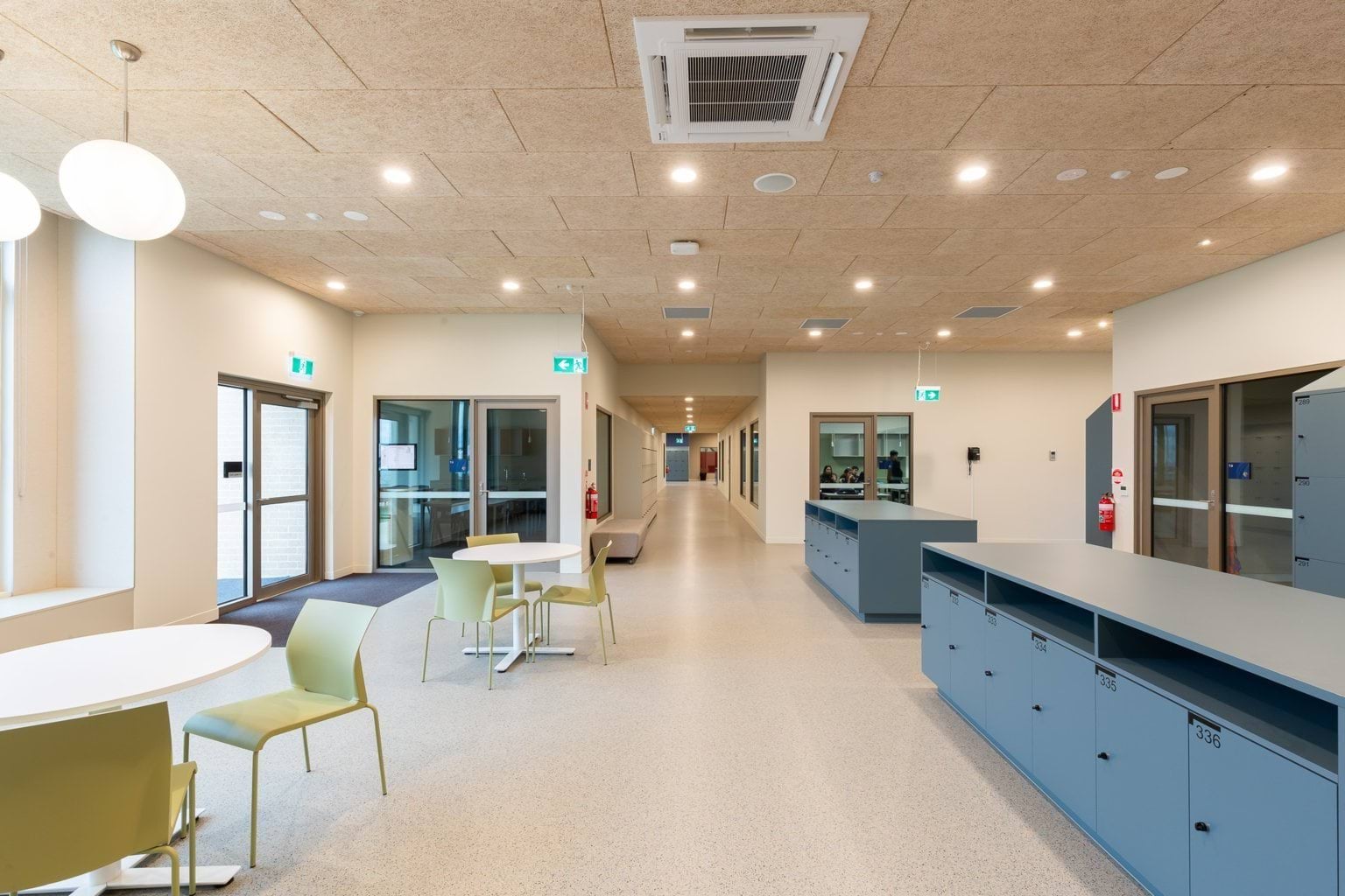 Hallway of building with lockers and tables and chairs 