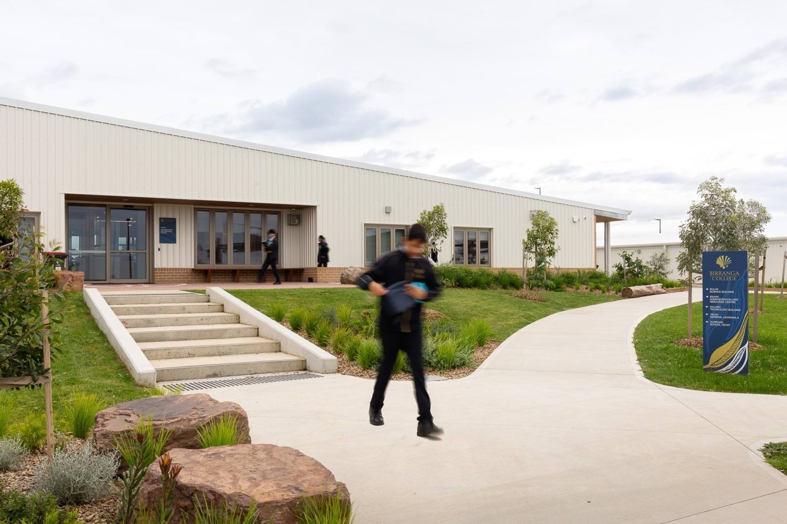Student walking along paved area outside school building