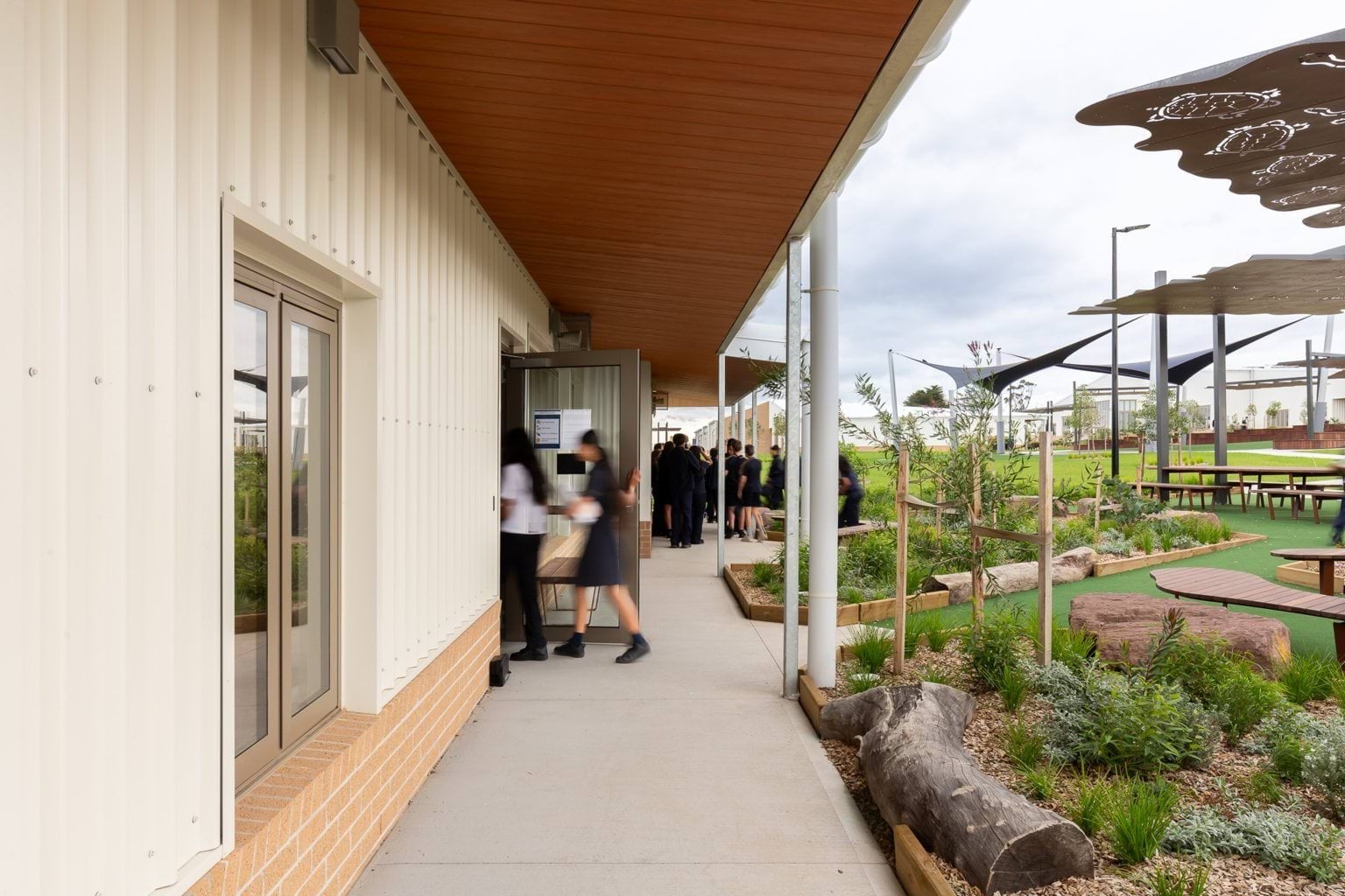 Students enter building near garden area
