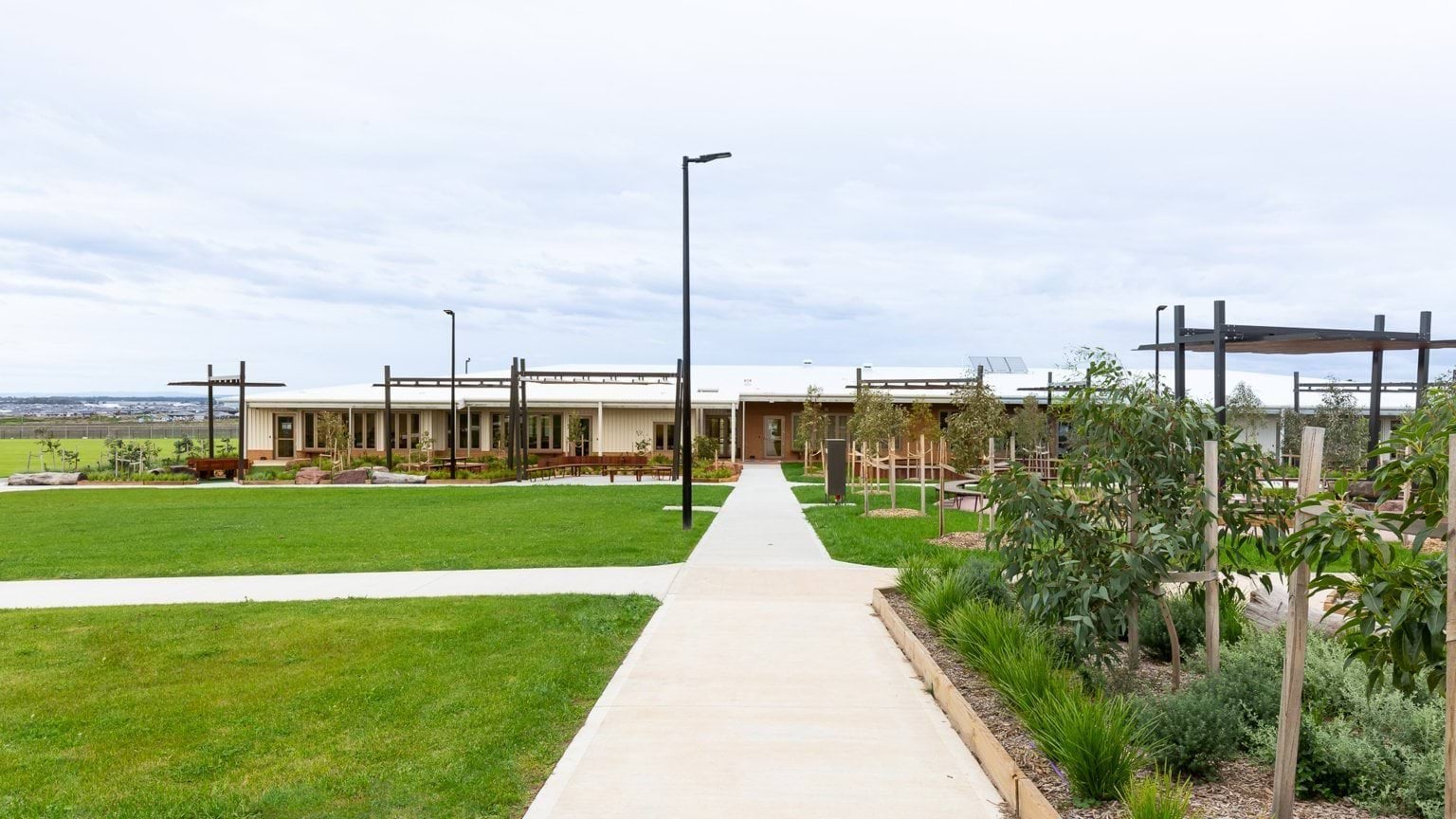 Footpath leading to school buildling surrounded by lawn and garden