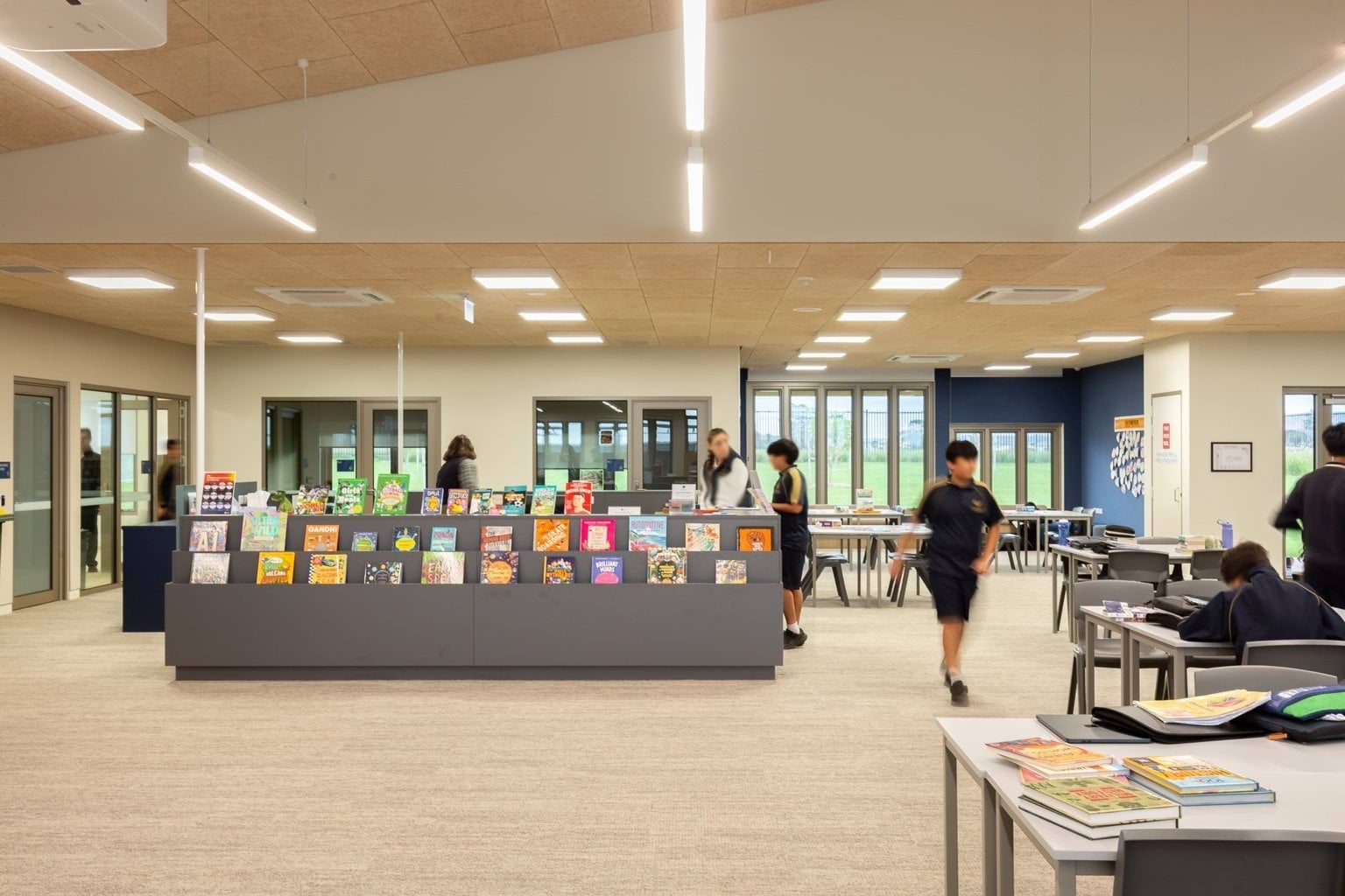 Students and teacher in central area with bookshelf and tables and chairs