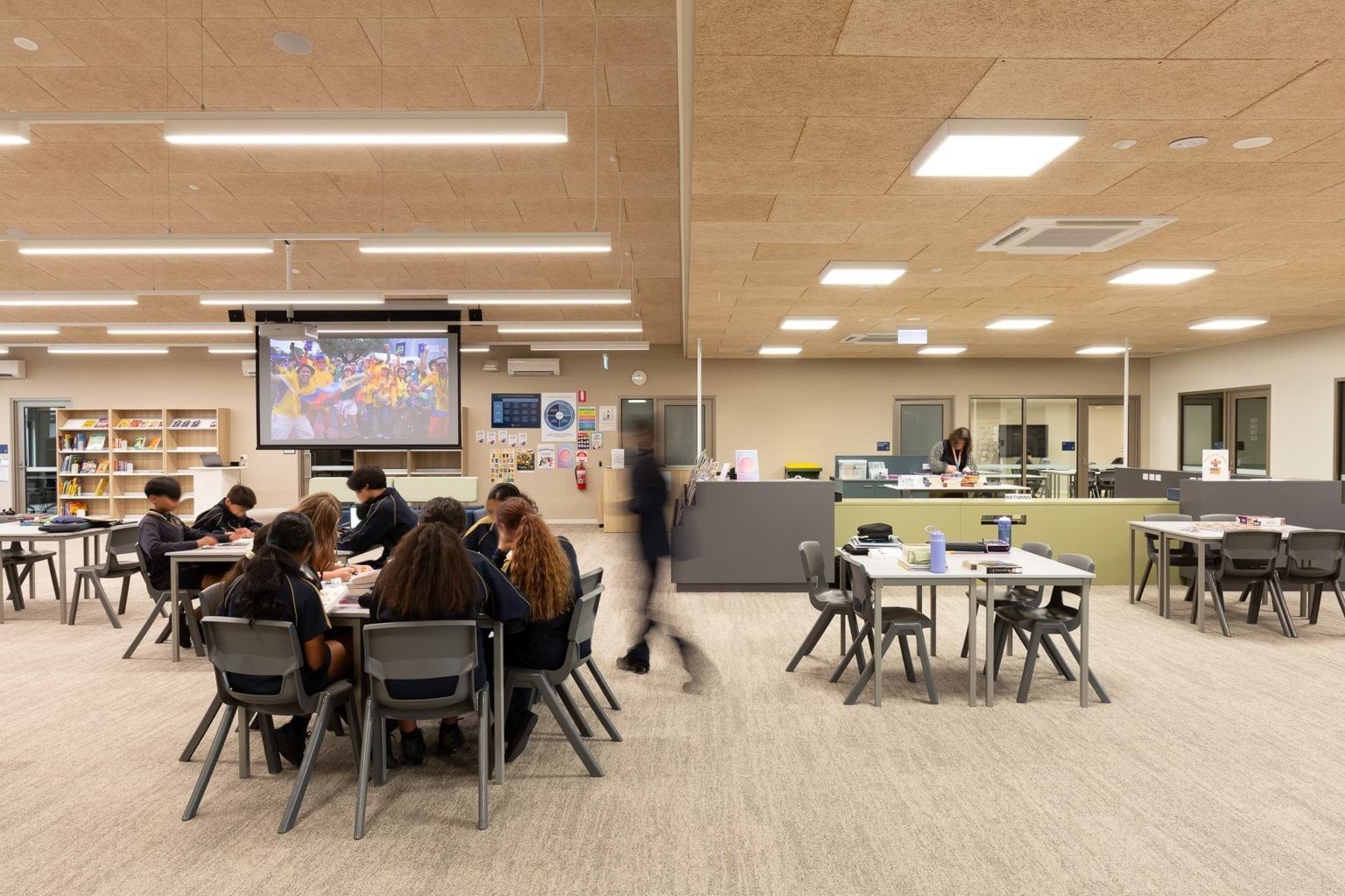 Students seated around tables in open classroom space