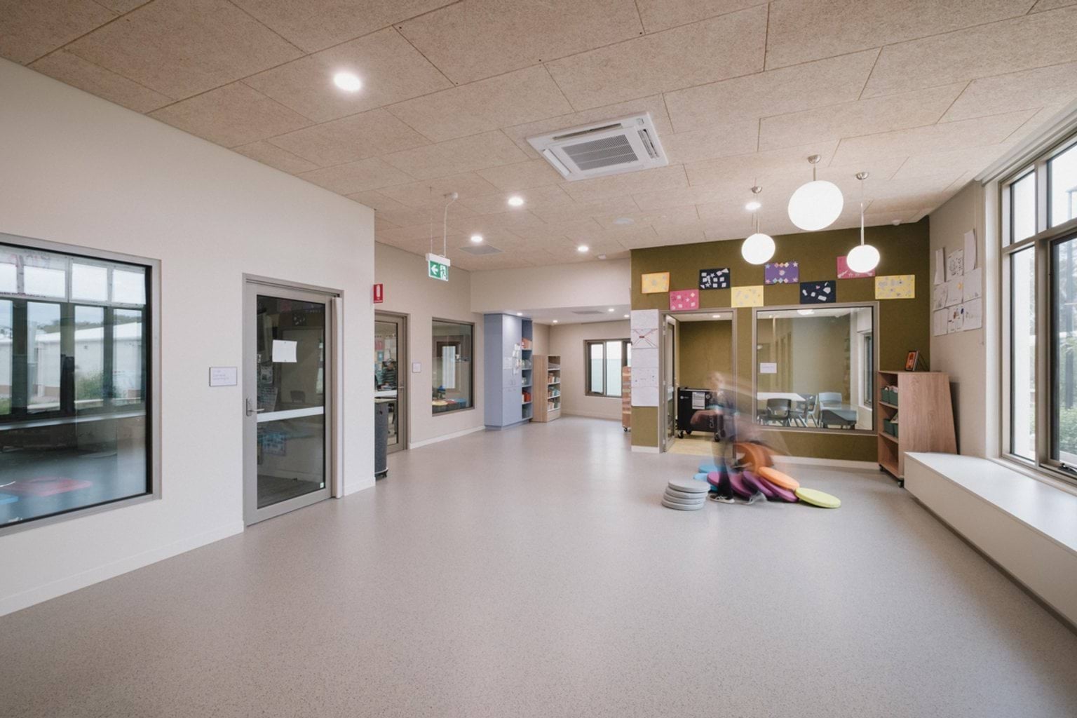 Open foyer area with white bench along window and doorways leading to classrooms and offices