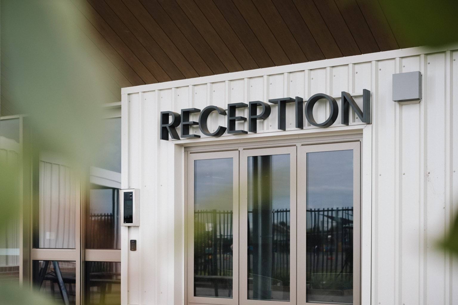 White building with doorway and large black lettering saying 'RECEPTION'