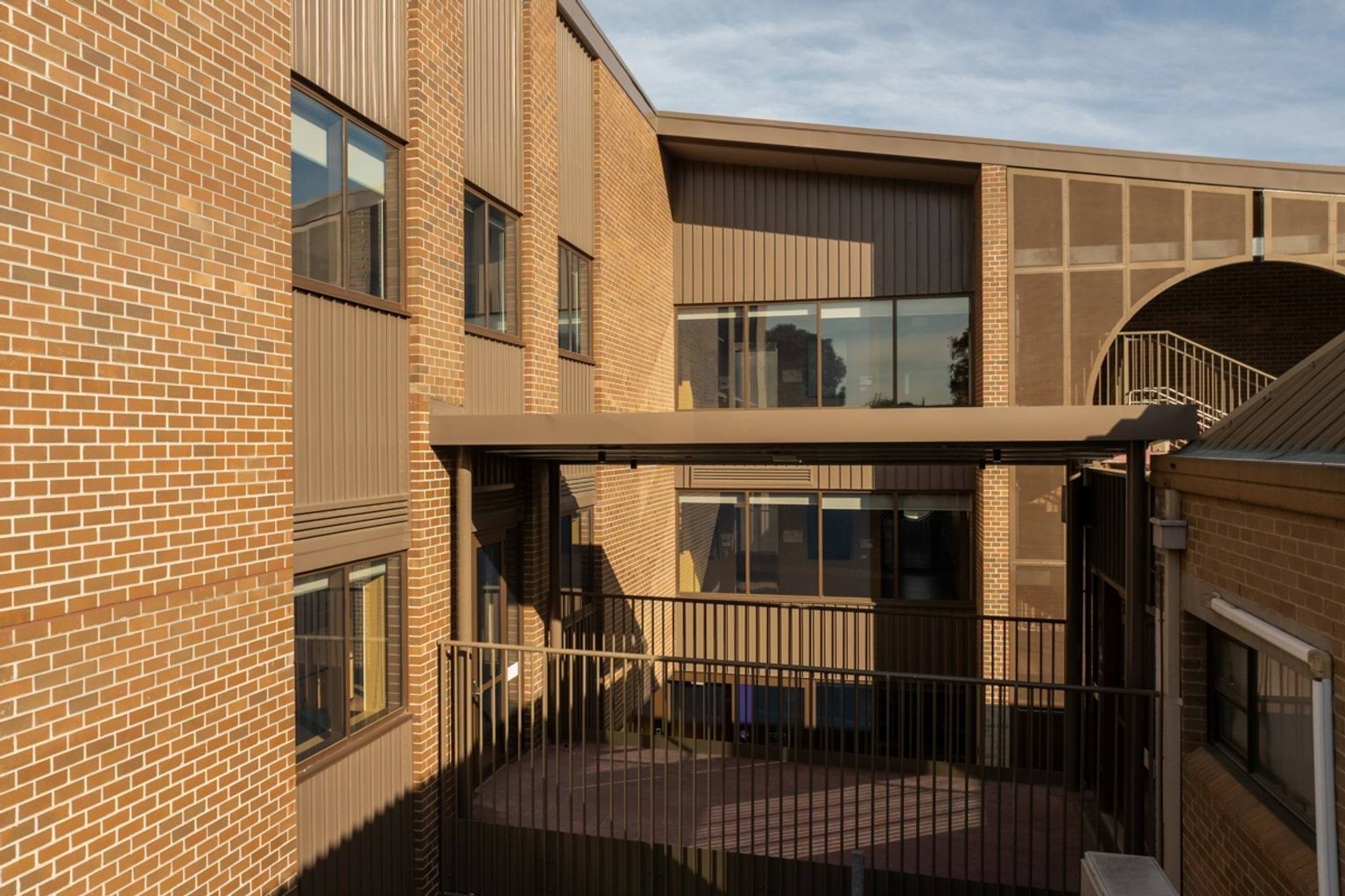 Brown brick buildings connected by brown metal sheltered walkway