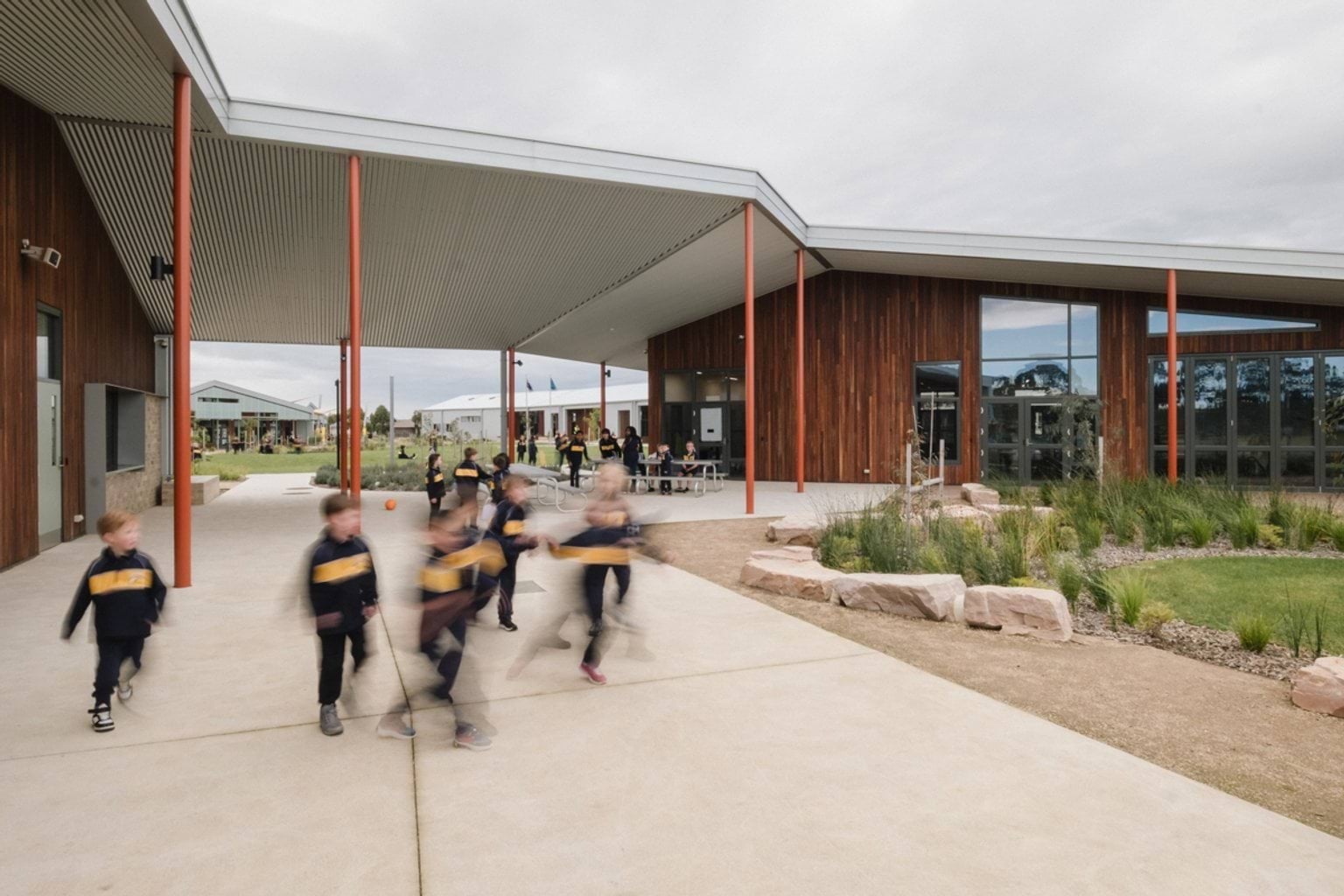 Students on paved area out the front of school building, next to garden area
