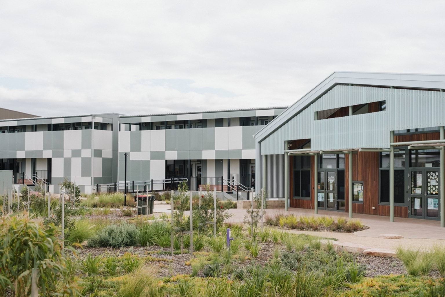 Paved area with garden beds throughout. We can see 3 school buildings in the background