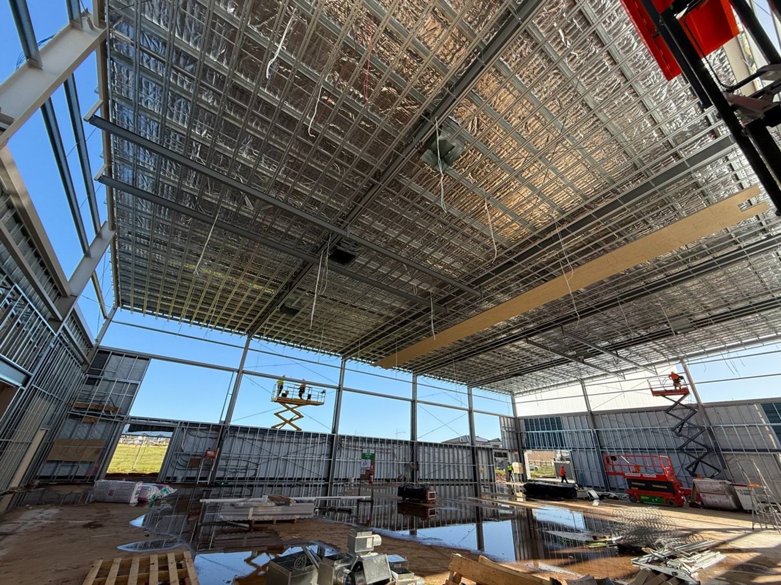 Partially completed building with exposed cladding and metal beams. We can see workers on