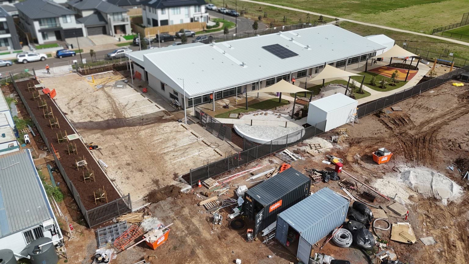 An aerial view of a construction site showing a large building, construction materials and site infrastructure nearing completion.