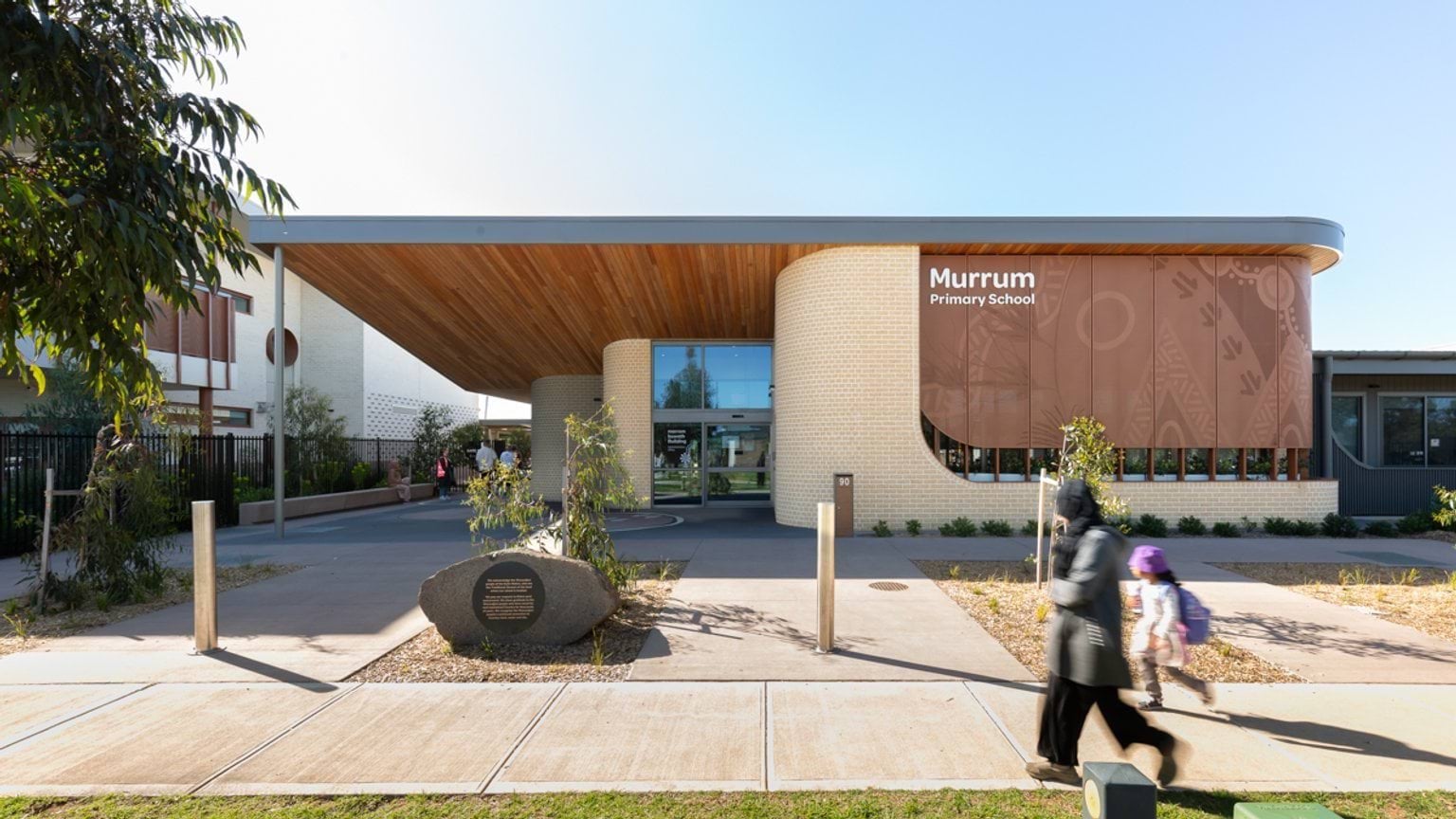 School entrance with paved walkways, landscaped garden areas and a large, modern school building